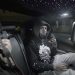 Treezy sits in the backseat of a car wearing a black hoodie, flashing a hand sign under star-lit ceiling lights—captured during a late-night creative session in Bridgeport, CT.