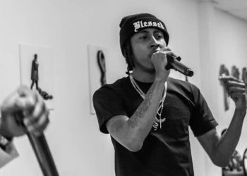 Infamous Moon performing live, holding a mic mid-verse in black and white.