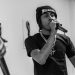 Infamous Moon performing live, holding a mic mid-verse in black and white.