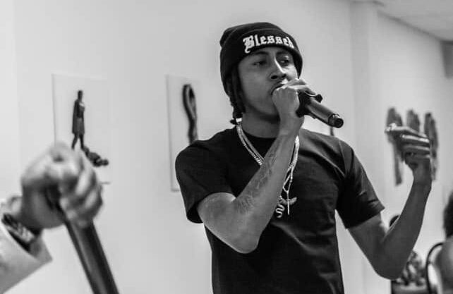 Infamous Moon performing live, holding a mic mid-verse in black and white.