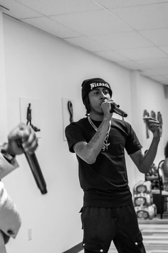 Infamous Moon performing live, holding a mic mid-verse in black and white.