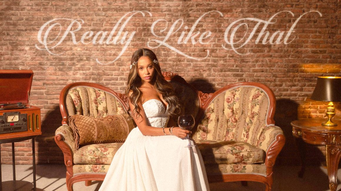 Kalabrya seated on a vintage sofa in the cover artwork for Really Like That