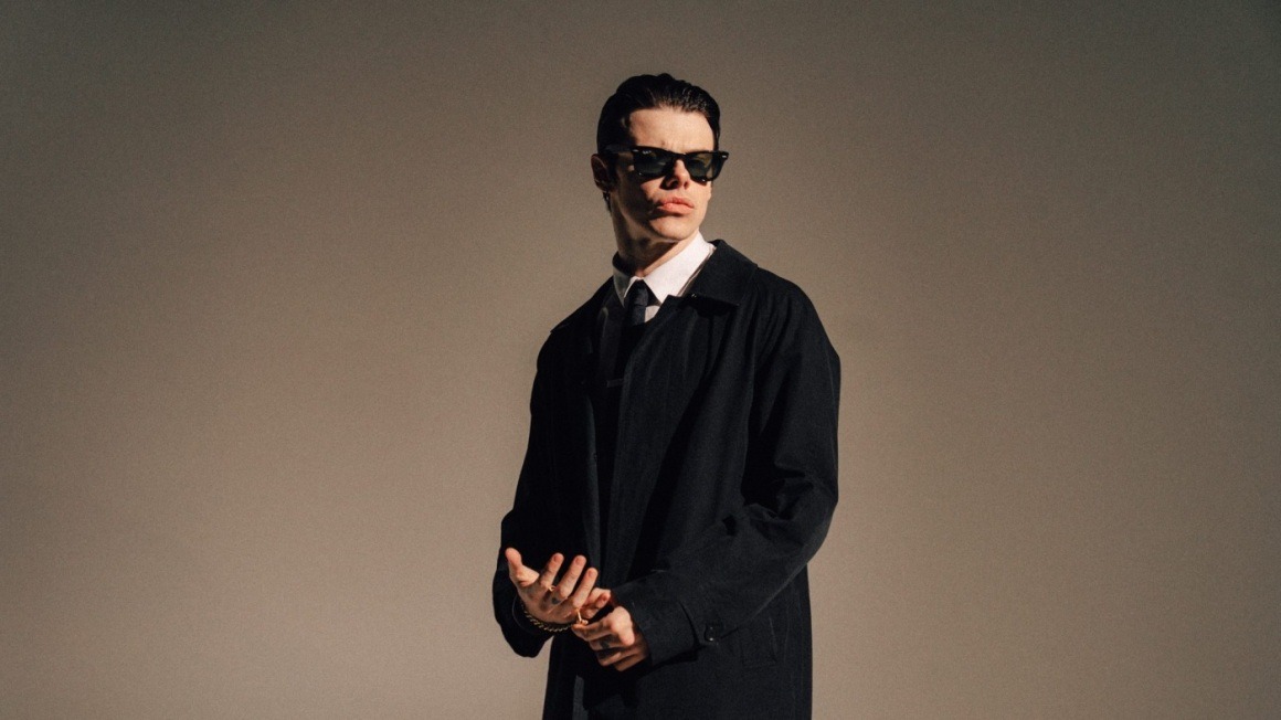 YUNGBLUD wearing sunglasses and a dark coat in a 2025 promotional portrait